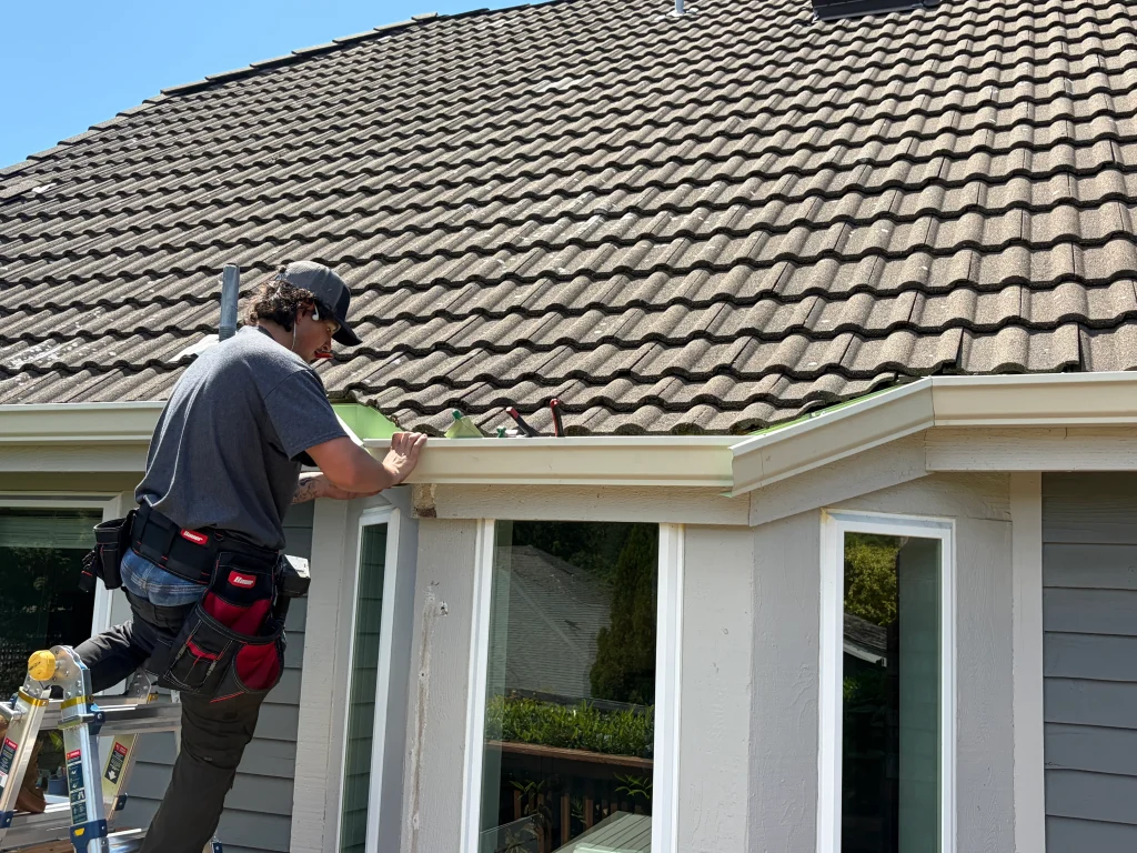 Solutionist fitting seamless gutters along a roofline from the ladder