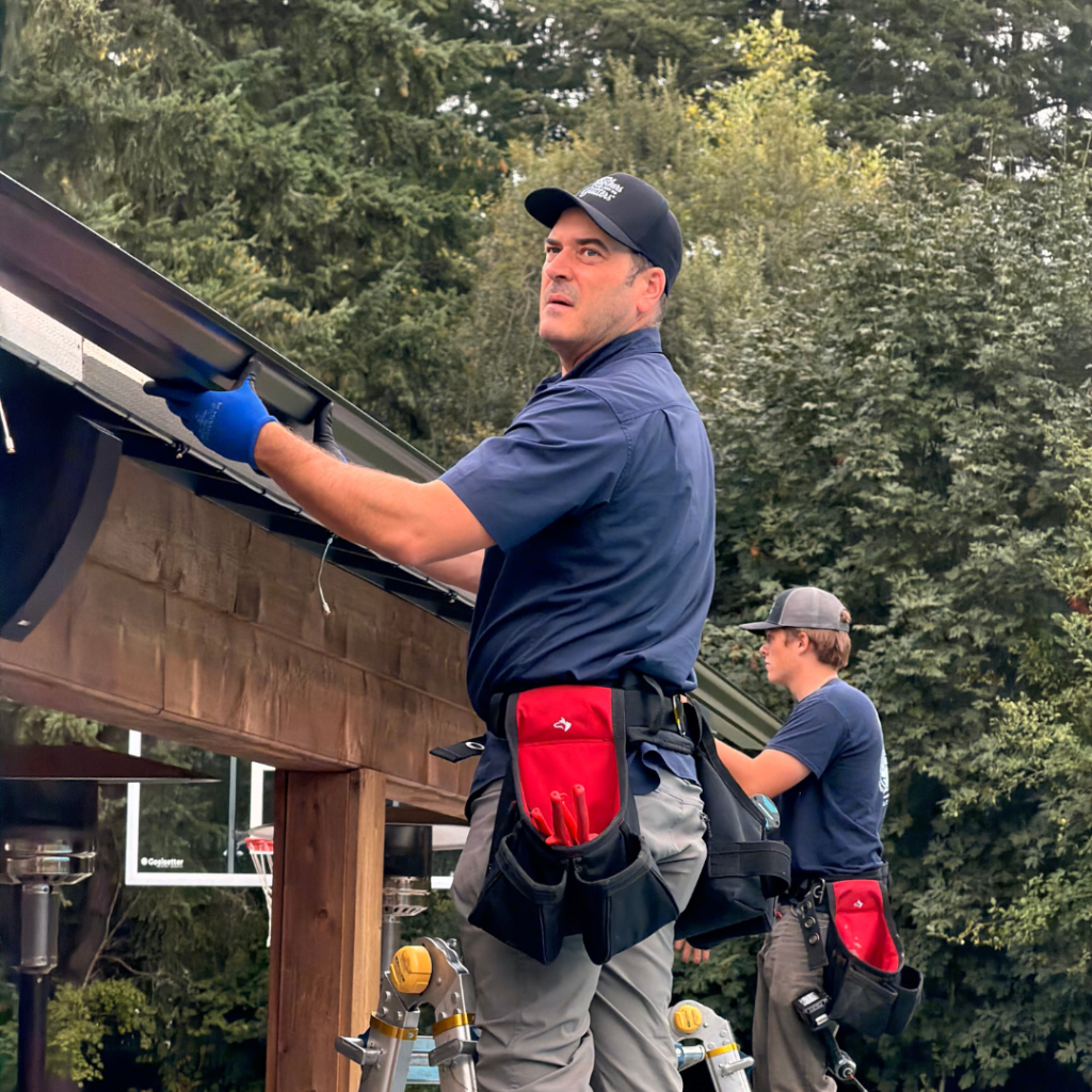 Zeke Edwards and a Solutionist installing seamless gutters on a Tacoma home