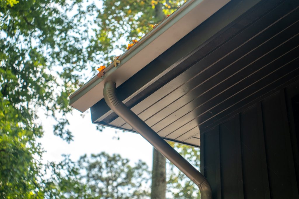 A dark box gutter and downspout under a wide eave