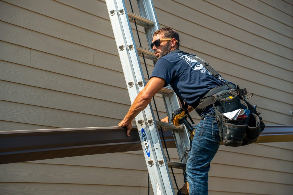 Carrying a new gutter up the ladder