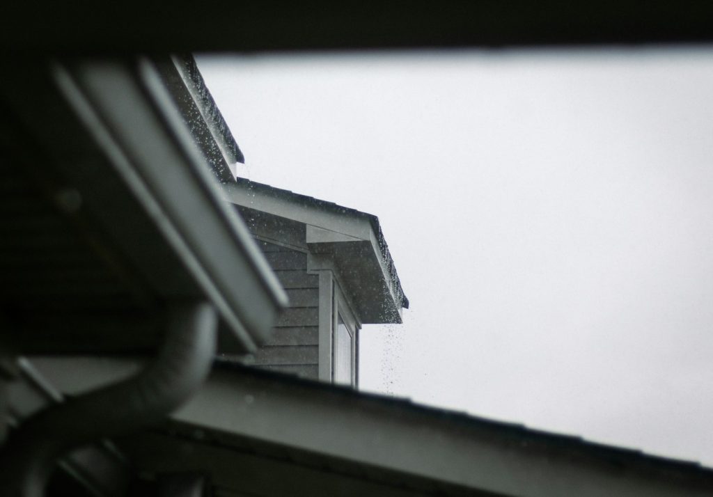 Looking up at a gutter under a gray, rainy sky